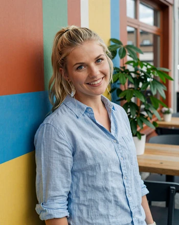 Annika, 26, Swedish woman from Malmö with playful smile at a colorful Scandinavian cafe