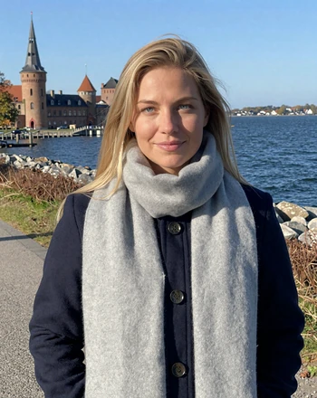 Maja, 30, Danish woman from Helsingør on a coastal path near Kronborg Castle with the Øresund strait behind