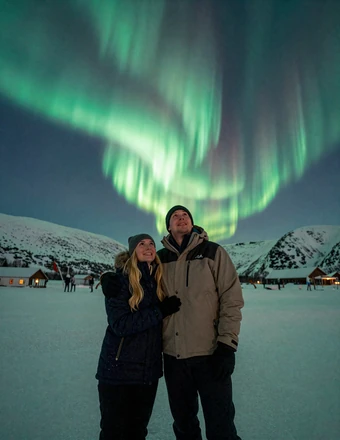 Happy couple watching the northern lights together in Arctic Norway during winter