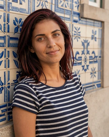 Inês, 29, Portuguese woman from Lisbon with soft smile leaning against azulejo tiles in Alfama