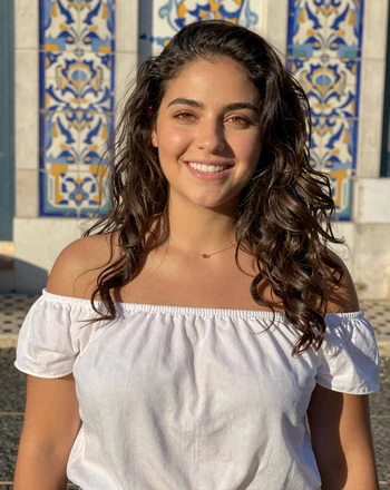 Elena, 28, Portuguese woman from Lisbon smiling against colorful azulejo tiles