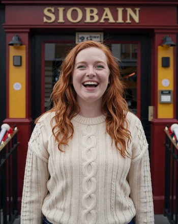 Siobhan, 27, Irish woman from Dublin with a bright laugh in front of a colorful pub