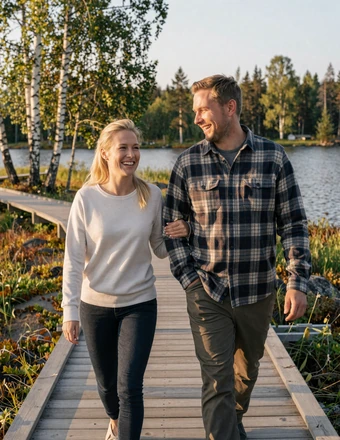 Happy American-Finnish couple walking on a wooden boardwalk through Finnish lakeland in summer